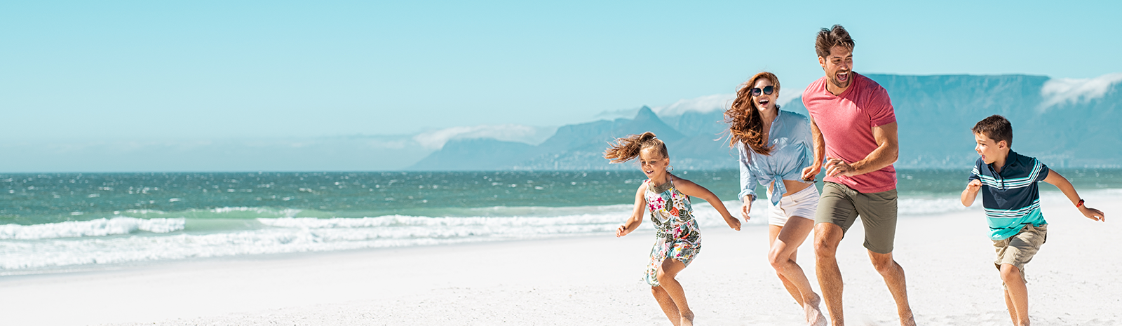 Family of four running down the beach
